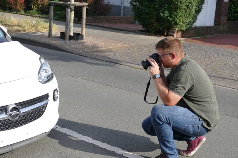 Kfz-Sachverständiger bei der Fotodokumentation eines Fahrzeugschadens vor Ort